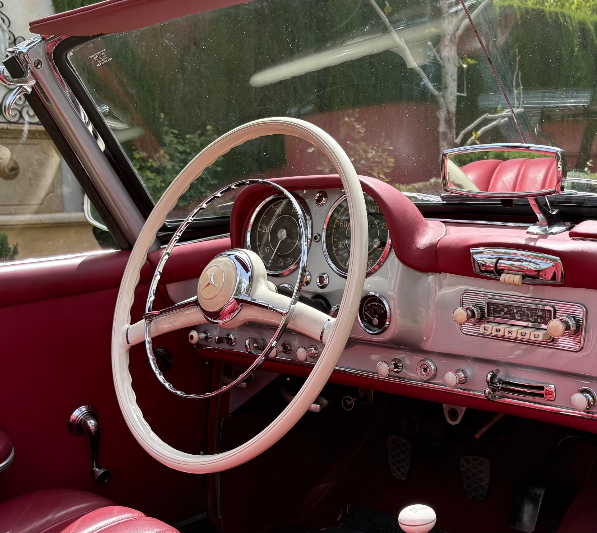 Interior del Mercedes 190 SL con volante blanco y tapicería granate